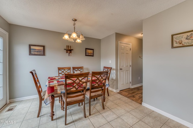 dining space featuring visible vents, a textured ceiling, a chandelier, and light tile patterned flooring