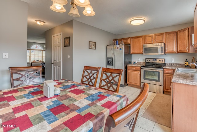 kitchen featuring an inviting chandelier, light tile patterned flooring, a sink, light countertops, and appliances with stainless steel finishes