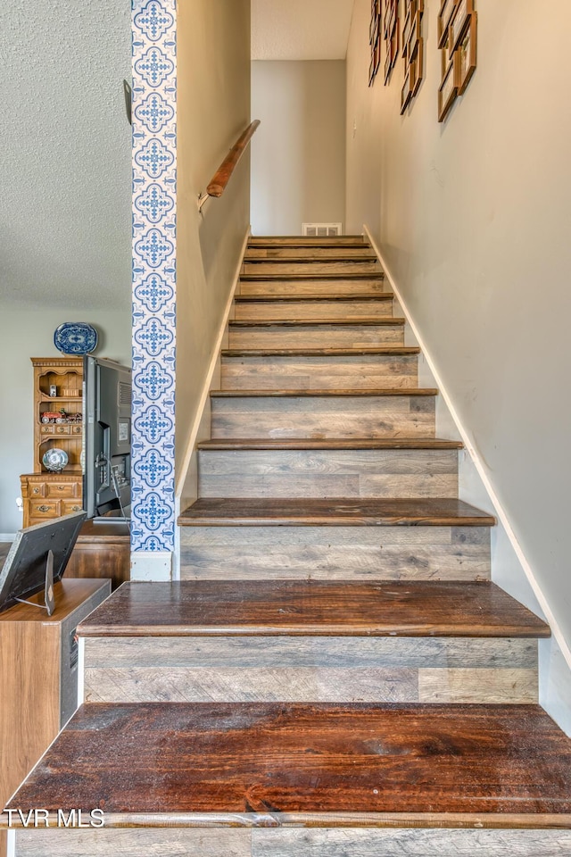 staircase with visible vents and a textured ceiling