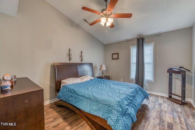 bedroom with visible vents, wood finished floors, baseboards, and vaulted ceiling