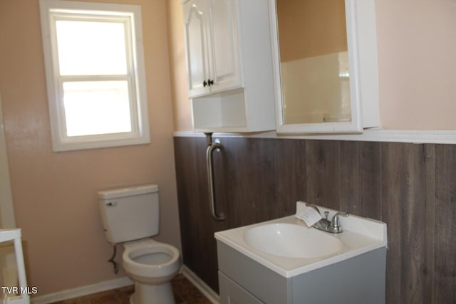 bathroom with wooden walls, toilet, and vanity