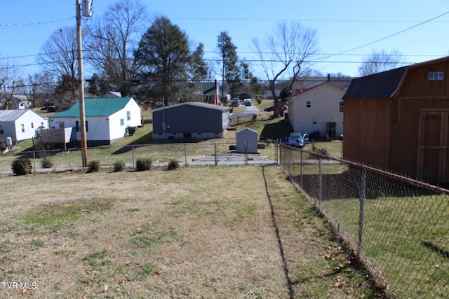 view of yard featuring a residential view, an outbuilding, a storage shed, and fence