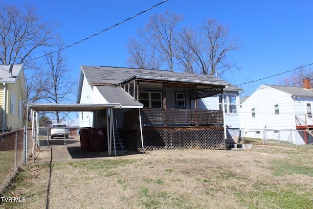 rear view of house with a gate, a yard, a shingled roof, a carport, and fence private yard