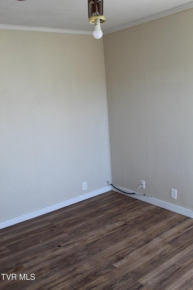 empty room featuring dark wood-style floors, baseboards, and ornamental molding