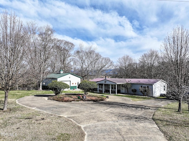 view of front of home featuring aphalt driveway, a detached garage, and a front yard