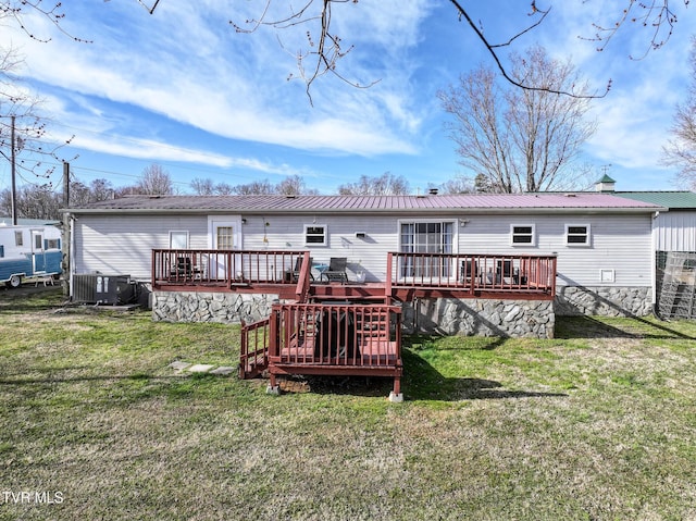 rear view of house with a wooden deck, central air condition unit, a lawn, and metal roof