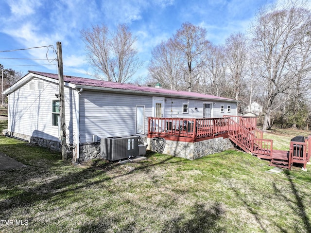 back of property with a deck, central air condition unit, a lawn, and metal roof