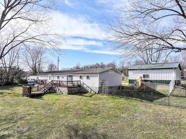 back of house with metal roof, a lawn, a deck, and fence