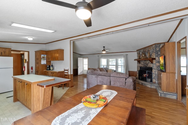 dining area featuring a fireplace, a textured ceiling, ceiling fan, and ornamental molding