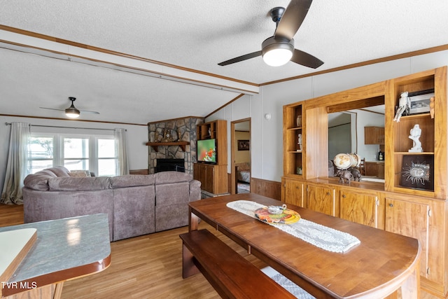 dining area with a textured ceiling, a fireplace, crown molding, and vaulted ceiling