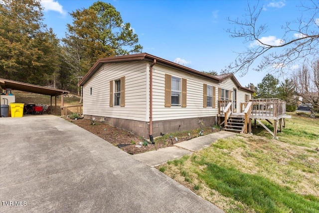 view of side of home featuring a deck, a lawn, and driveway