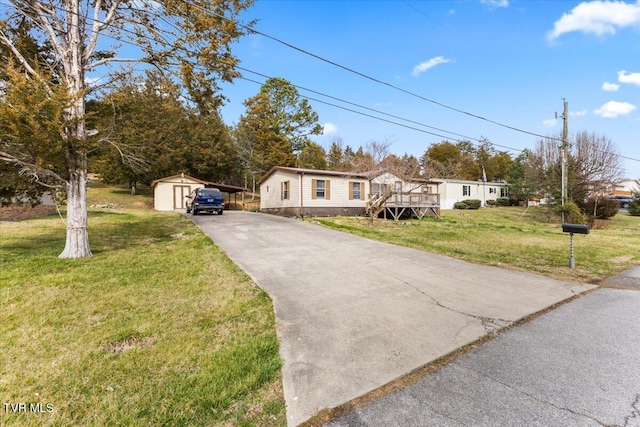 manufactured / mobile home with an outdoor structure, a carport, a front yard, and driveway