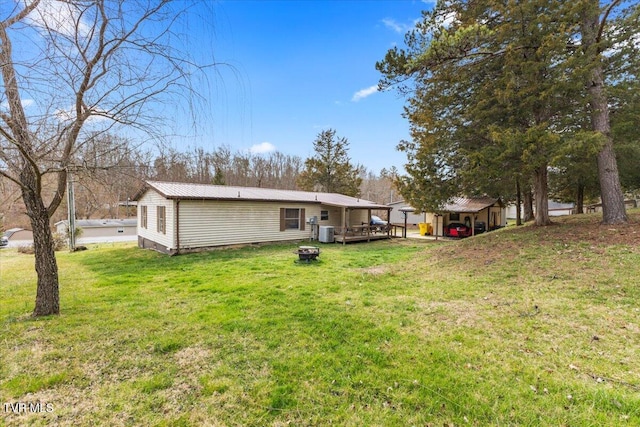 back of property with a deck, an outdoor fire pit, a yard, and metal roof