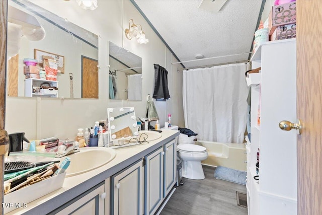 bathroom featuring visible vents, toilet, vanity, shower / bath combination with curtain, and a textured ceiling