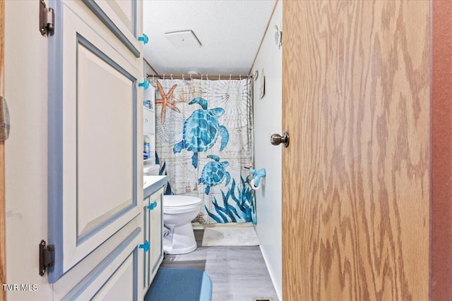 bathroom with vanity, a shower with curtain, toilet, and wood finished floors