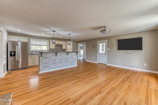 unfurnished living room featuring a wealth of natural light, recessed lighting, baseboards, and light wood-style floors