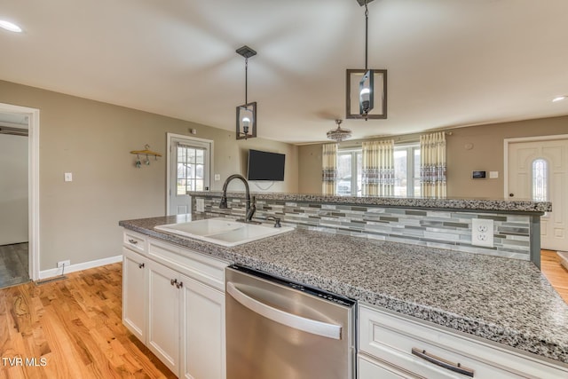 kitchen featuring light wood-style flooring, a sink, white cabinets, decorative backsplash, and dishwasher