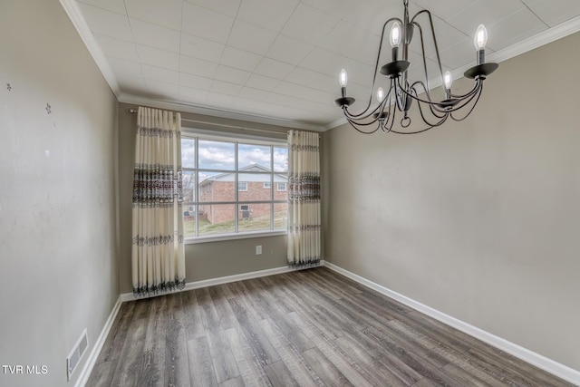 spare room with visible vents, crown molding, baseboards, a chandelier, and wood finished floors