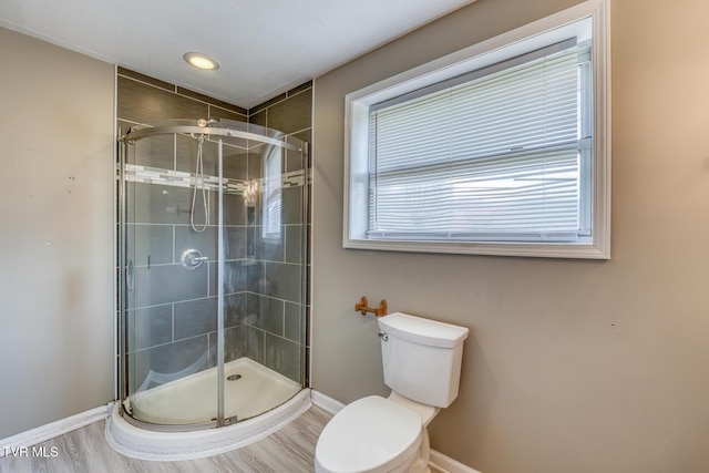 full bath featuring wood finished floors, toilet, baseboards, and a stall shower