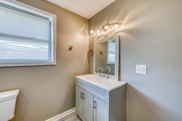 bathroom featuring vanity, toilet, and baseboards