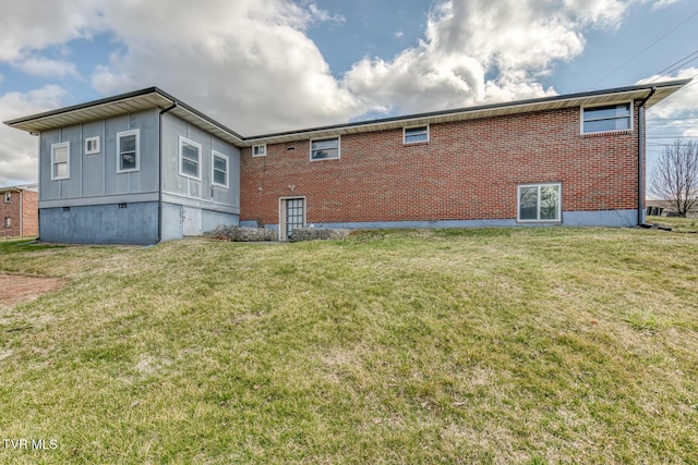 rear view of property with brick siding and a yard