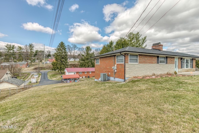 back of house featuring a yard, fence, brick siding, and a chimney