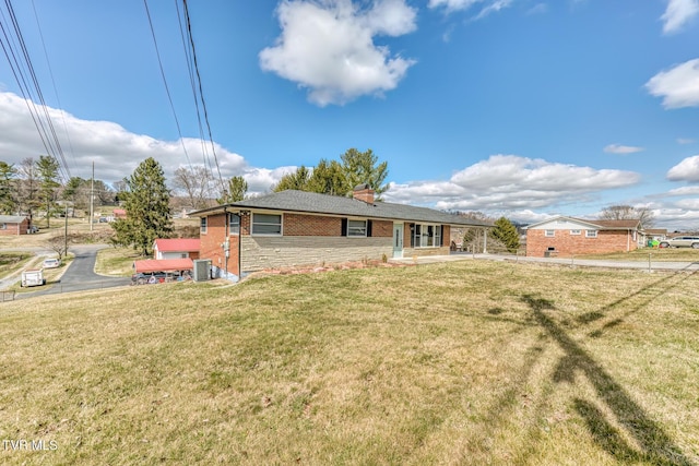 view of front of home with central air condition unit, brick siding, a chimney, and a front yard