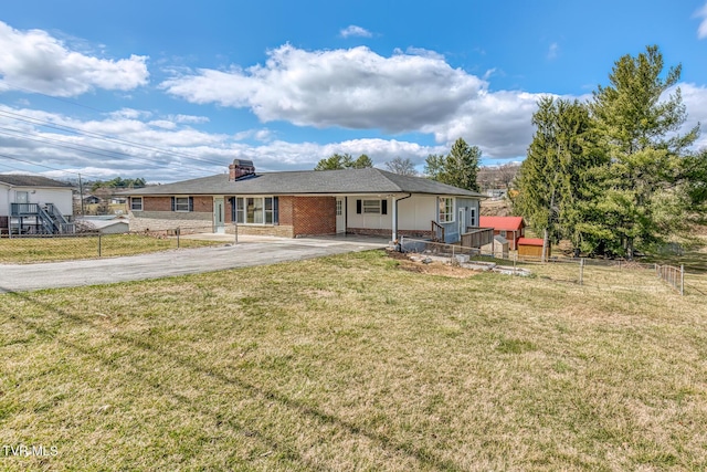 view of front of house featuring driveway, brick siding, a front lawn, and fence