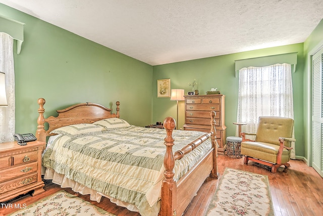 bedroom with a closet, wood-type flooring, and a textured ceiling