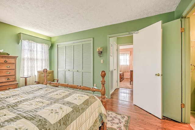 bedroom featuring light wood-style flooring, a closet, and a textured ceiling