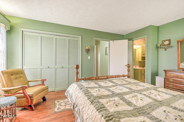 bedroom featuring a closet, a textured ceiling, wood finished floors, and ensuite bathroom