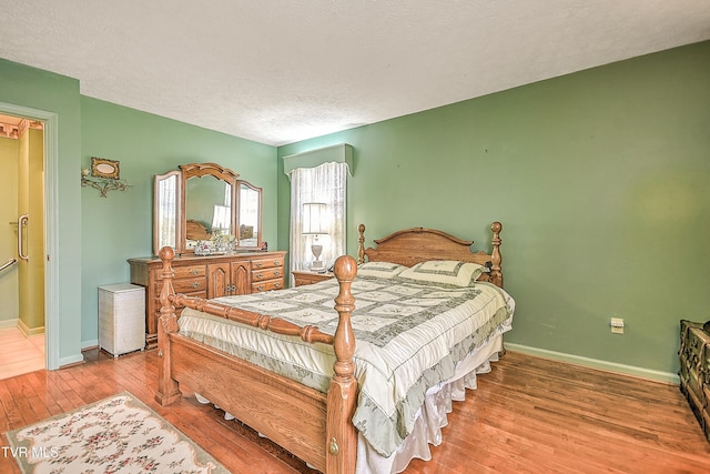 bedroom featuring a textured ceiling, baseboards, and wood finished floors