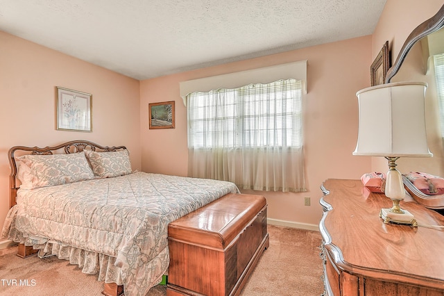 bedroom with baseboards, light carpet, and a textured ceiling