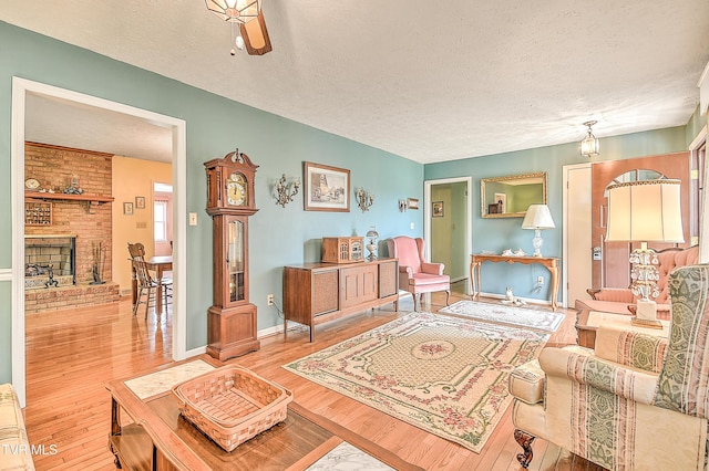 living area with a fireplace, a textured ceiling, baseboards, and wood finished floors