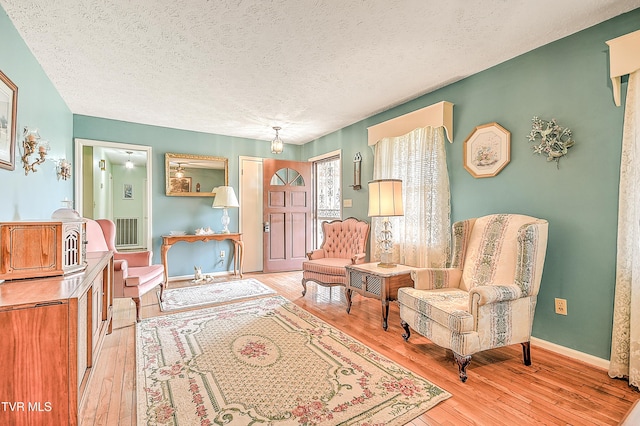 sitting room featuring a textured ceiling, baseboards, and light wood-style floors