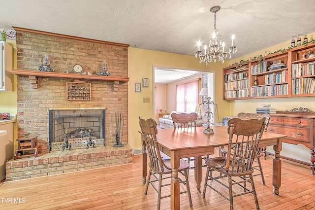 dining room featuring a fireplace, a textured ceiling, an inviting chandelier, and wood-type flooring