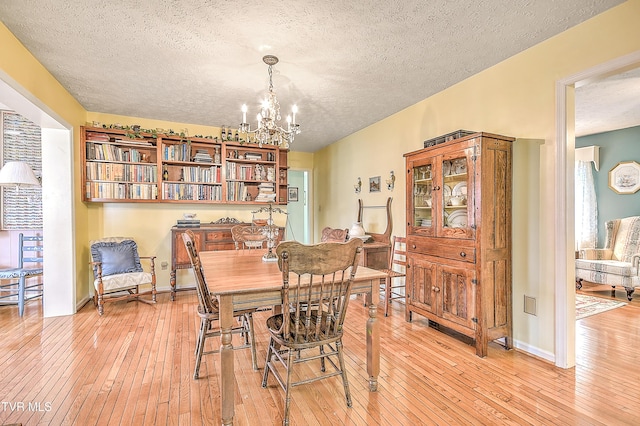 dining space featuring a notable chandelier, baseboards, and light wood-type flooring