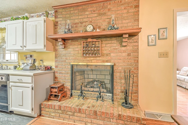 room details with a brick fireplace, wood finished floors, and visible vents