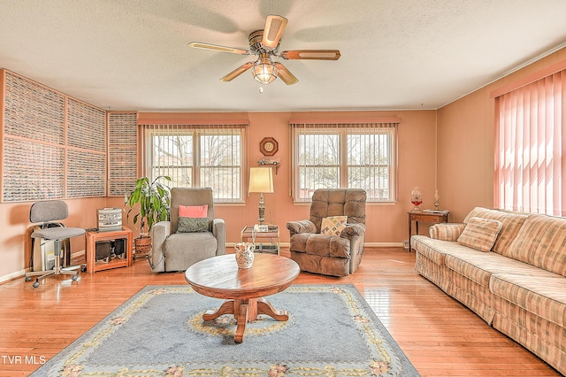 living area featuring baseboards, wood finished floors, a textured ceiling, and ceiling fan