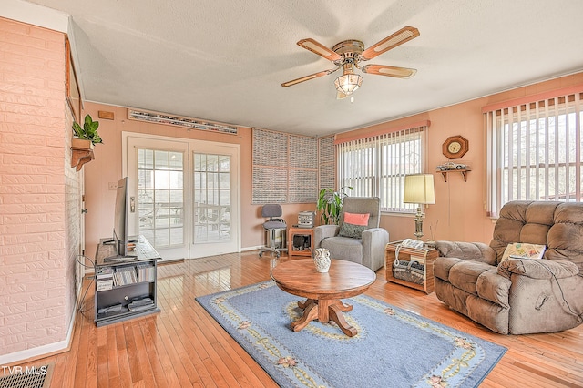 living room featuring hardwood / wood-style floors, a ceiling fan, visible vents, and a textured ceiling