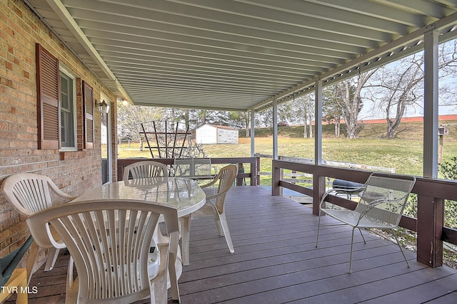 wooden deck featuring a yard, a storage shed, an outdoor structure, and outdoor dining space