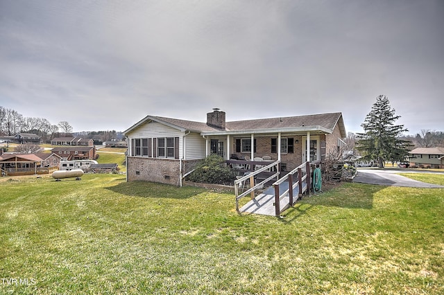 view of front facade featuring crawl space, brick siding, a chimney, and a front lawn