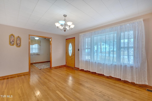 foyer entrance featuring a chandelier, a healthy amount of sunlight, baseboards, and wood finished floors