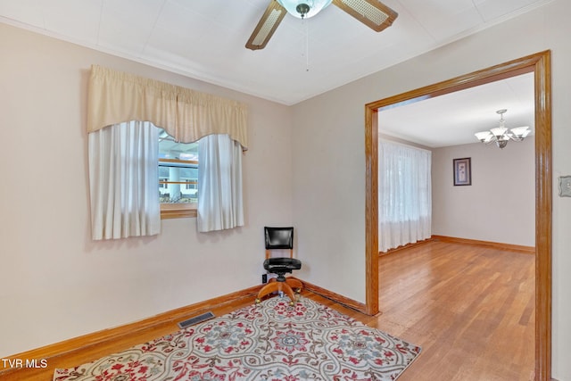 interior space with visible vents, baseboards, wood finished floors, and ceiling fan with notable chandelier