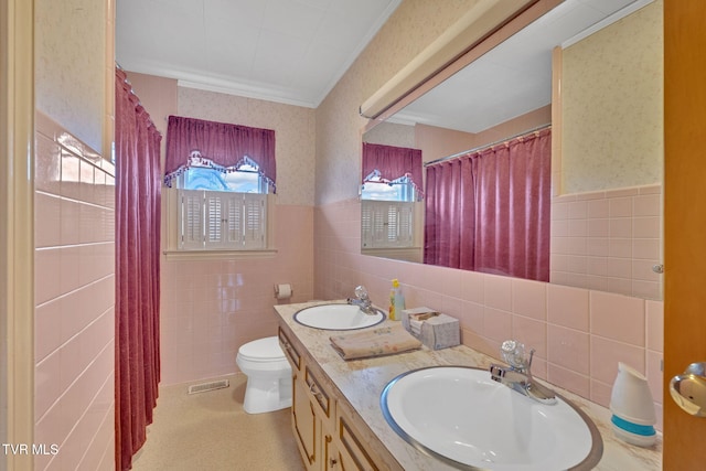 full bathroom with a sink, a wainscoted wall, visible vents, and wallpapered walls