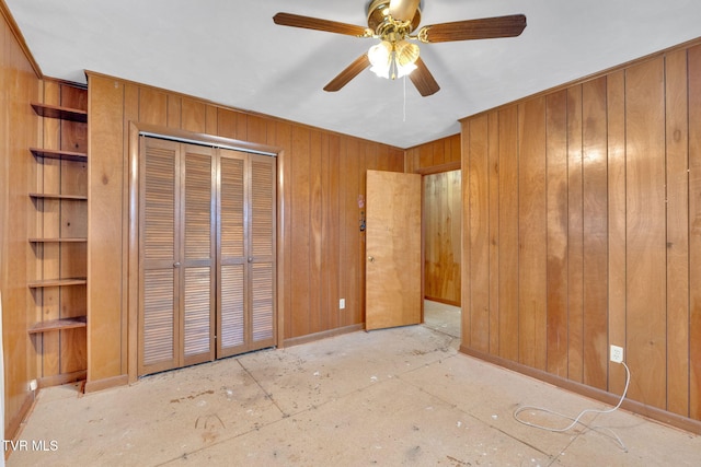 unfurnished bedroom featuring a closet, baseboards, wood walls, and a ceiling fan