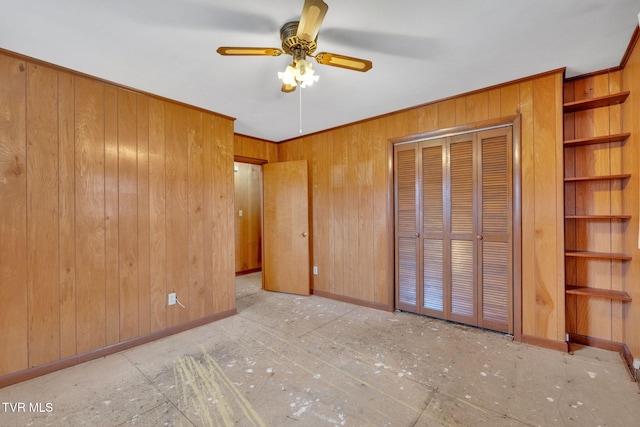 unfurnished bedroom with crown molding, wooden walls, baseboards, and a closet