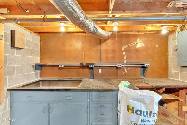 unfinished basement featuring a workshop area and concrete block wall