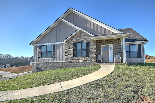 view of front of property featuring a front lawn, brick siding, board and batten siding, and stone siding