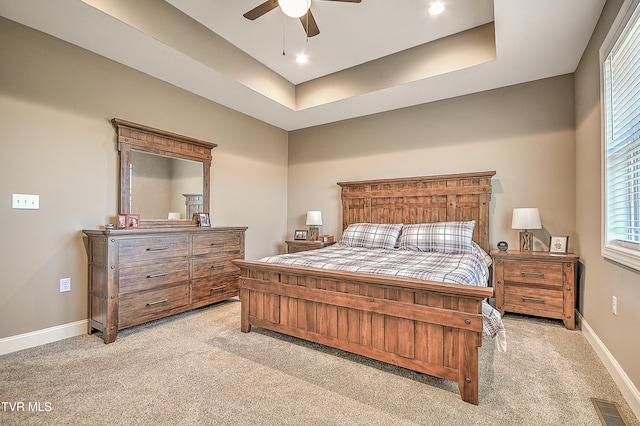 bedroom with visible vents, light carpet, a ceiling fan, baseboards, and a raised ceiling